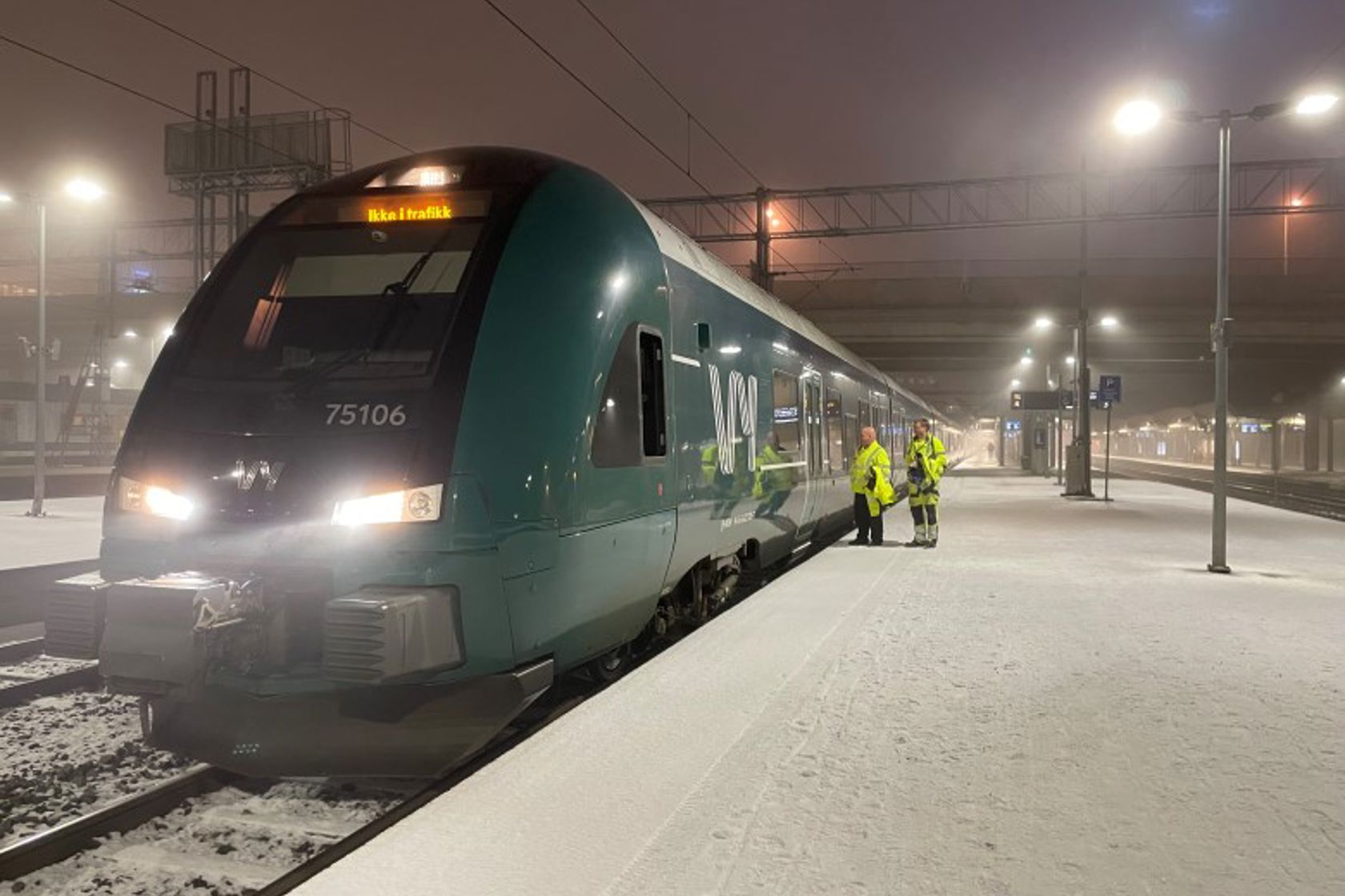 Bildet av et tog som står på perrongen en vinterkveld i januar.