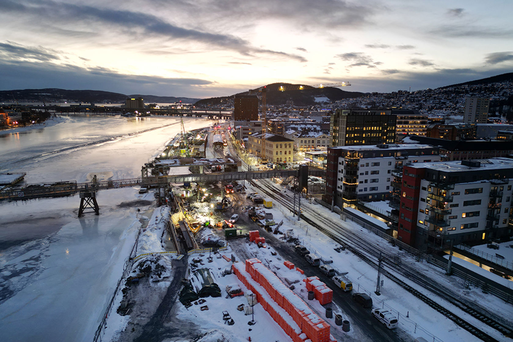  Byggeplass ved elv i vinterlandskap ved skumring.