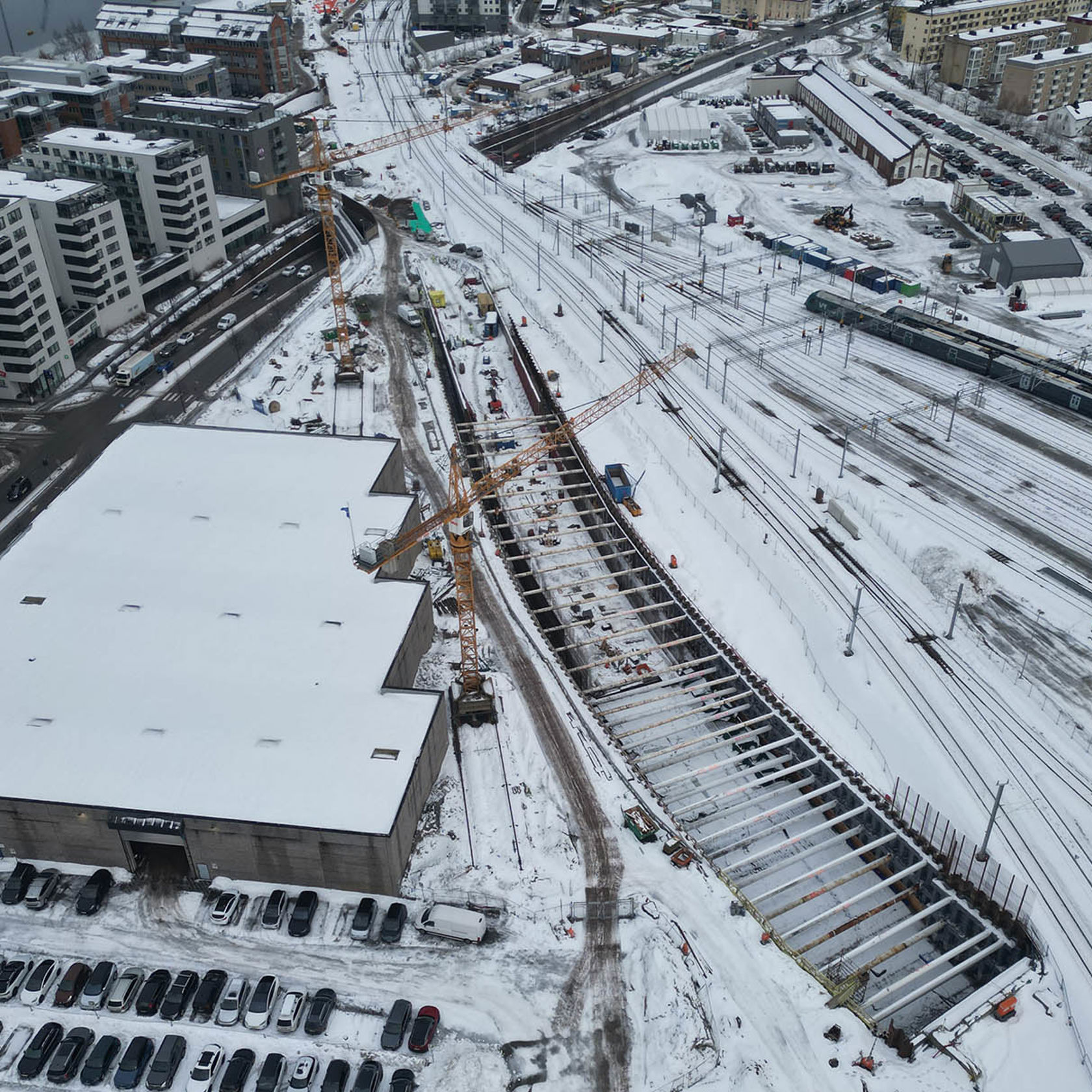  Byggeplass nær togspor med kraner og snø.