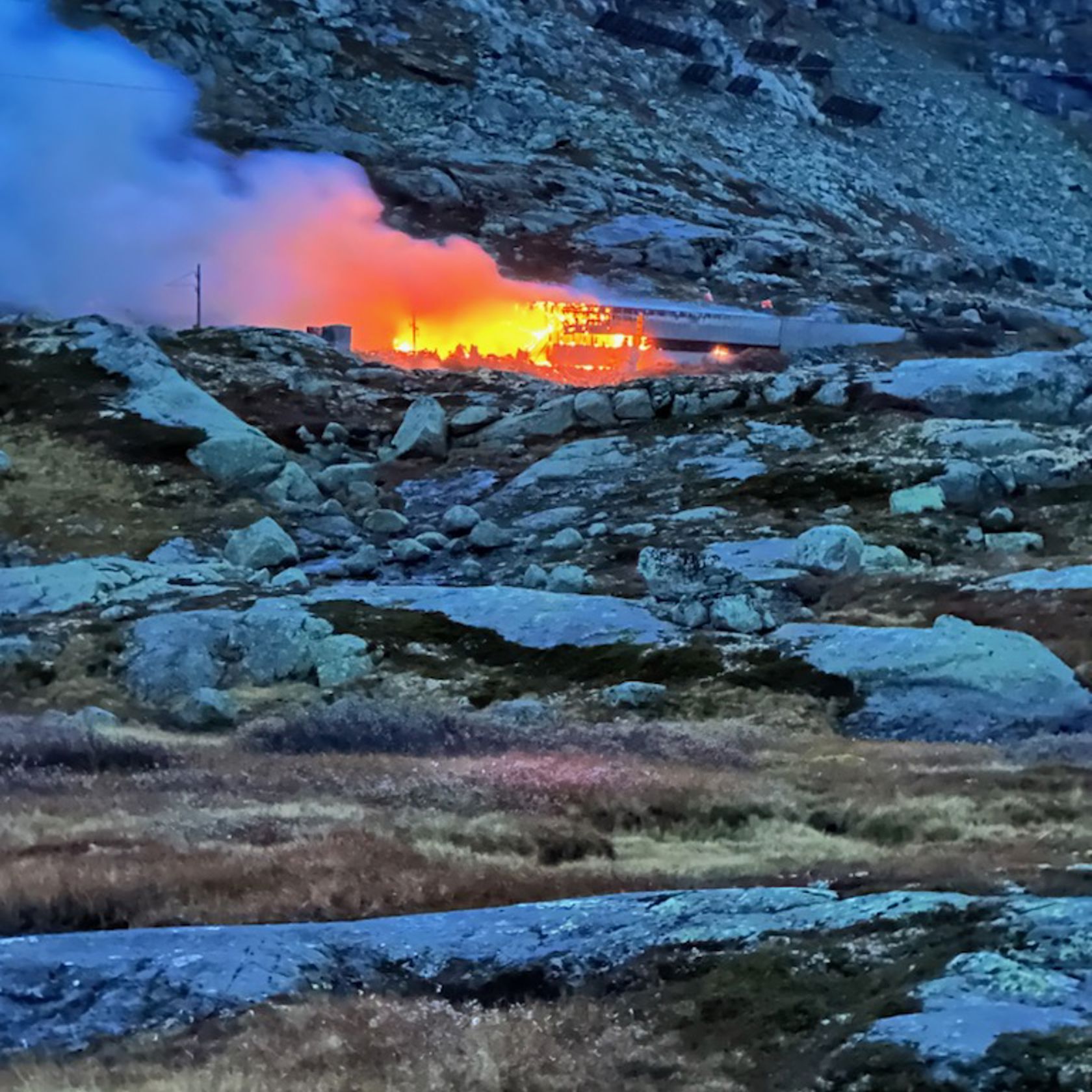 Rødgule flammer fra brann i bygning på fjellet