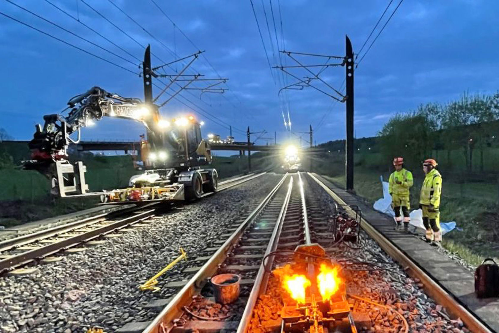 Skinnegående arbeidsmaskiner, skinnesveising, mannskaper i anleggsklær.