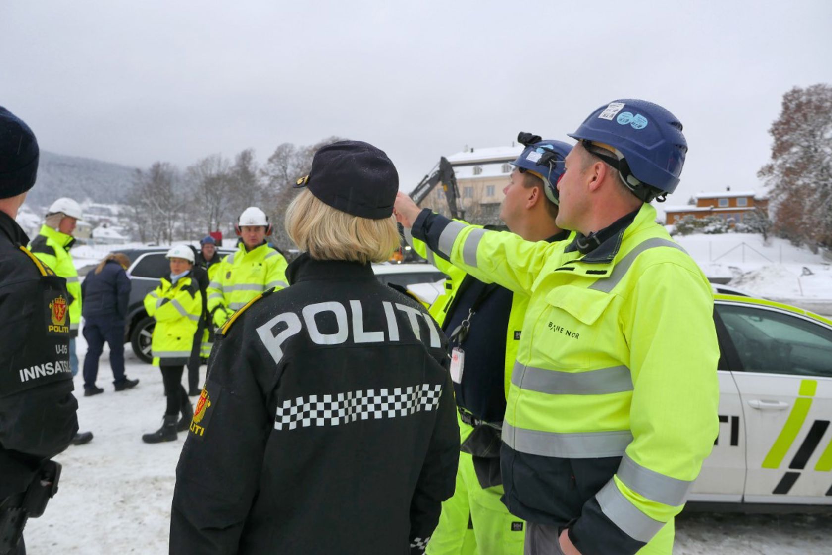 Bilde av mennesker i vernetøy og uniform på byggeplass 