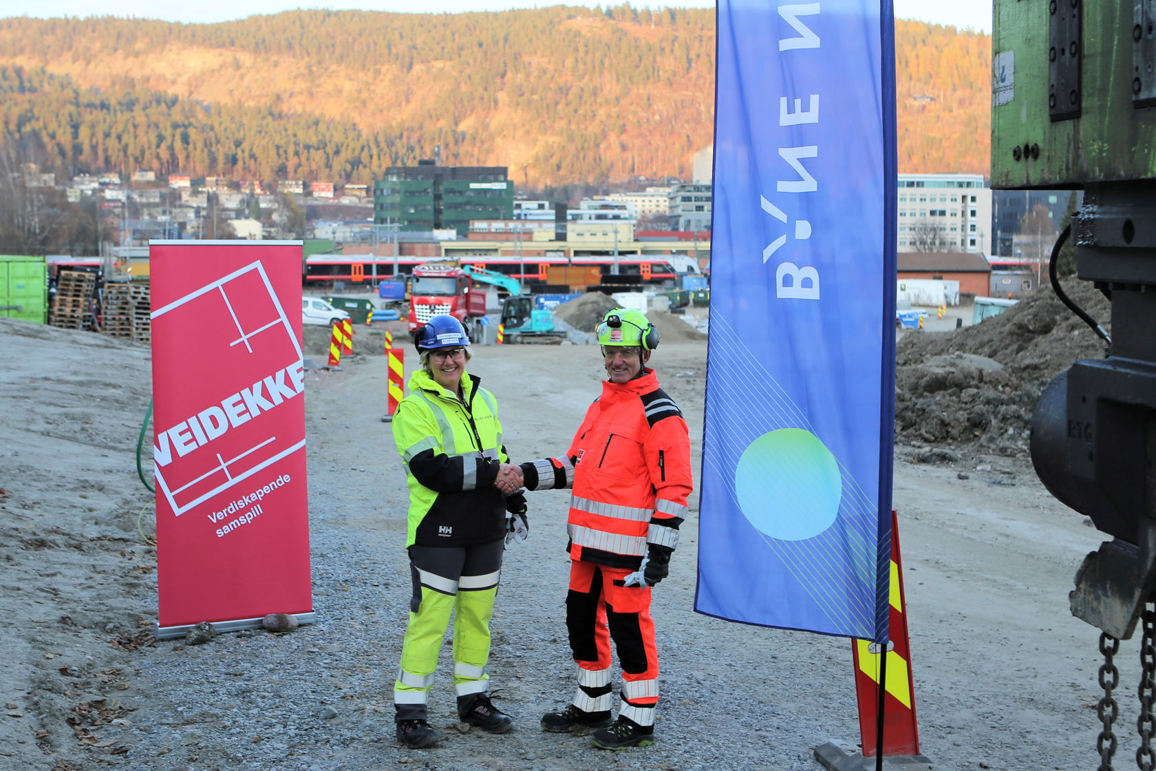 Bilde av to mennesker i vernetøy som tar hverandre i hånden.