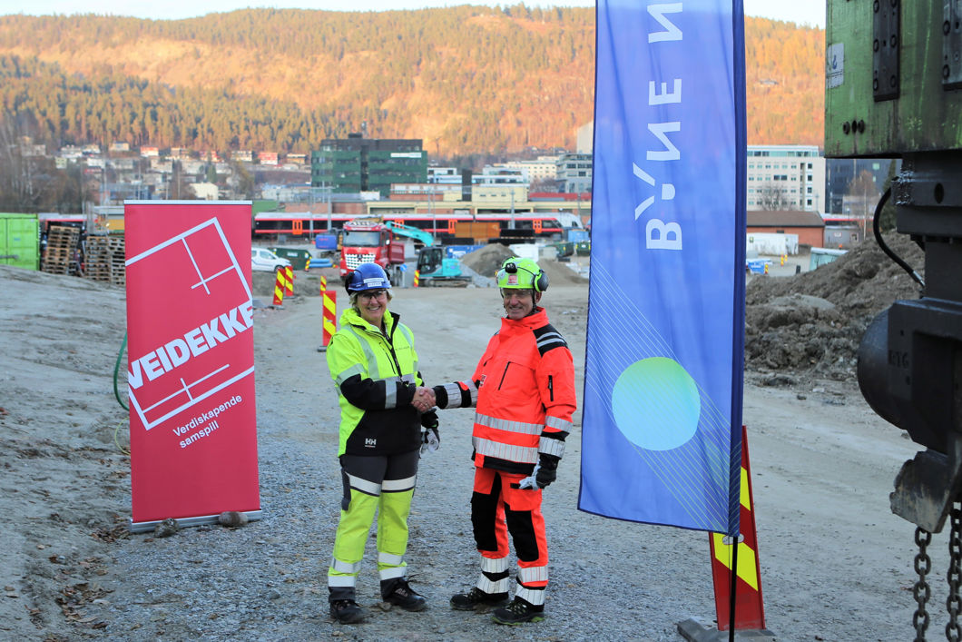 Bilde av to mennesker i vernetøy som tar hverandre i hånden.