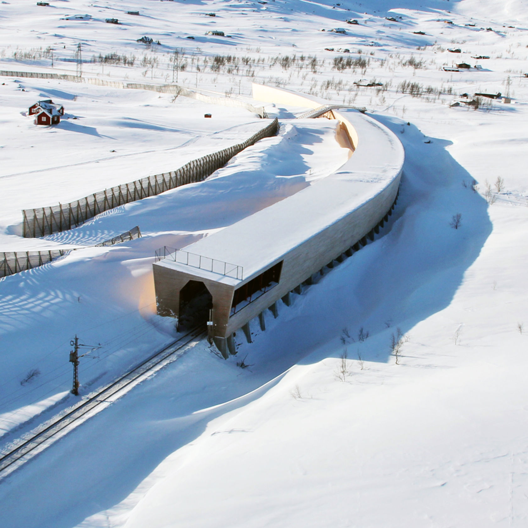 Snøoverbygg over skinnegangen i snødekt terreng.