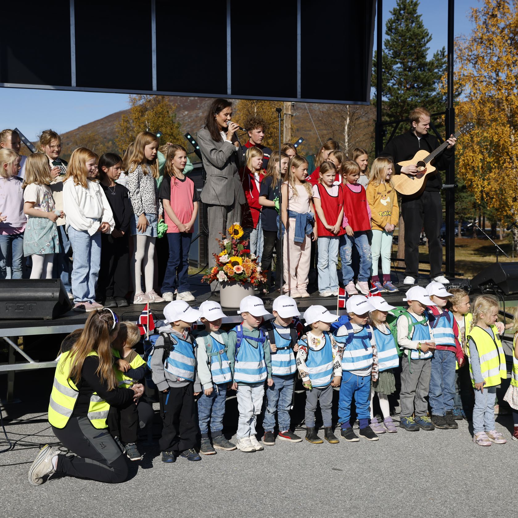 Voksne og barn synger på en scene