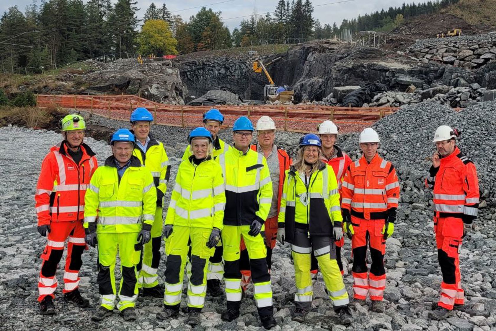 Representanter fra Veidekke og Bane NOR på befaring på den permanente fyllingen for nytt dobbeltspor. I bakgrunnen ligger byggegropen der tunnelmunningen kommer.