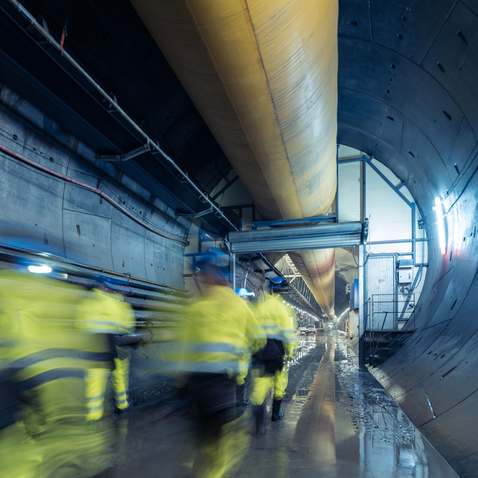 Folk i arbeidsklær går innover i en tunnel.