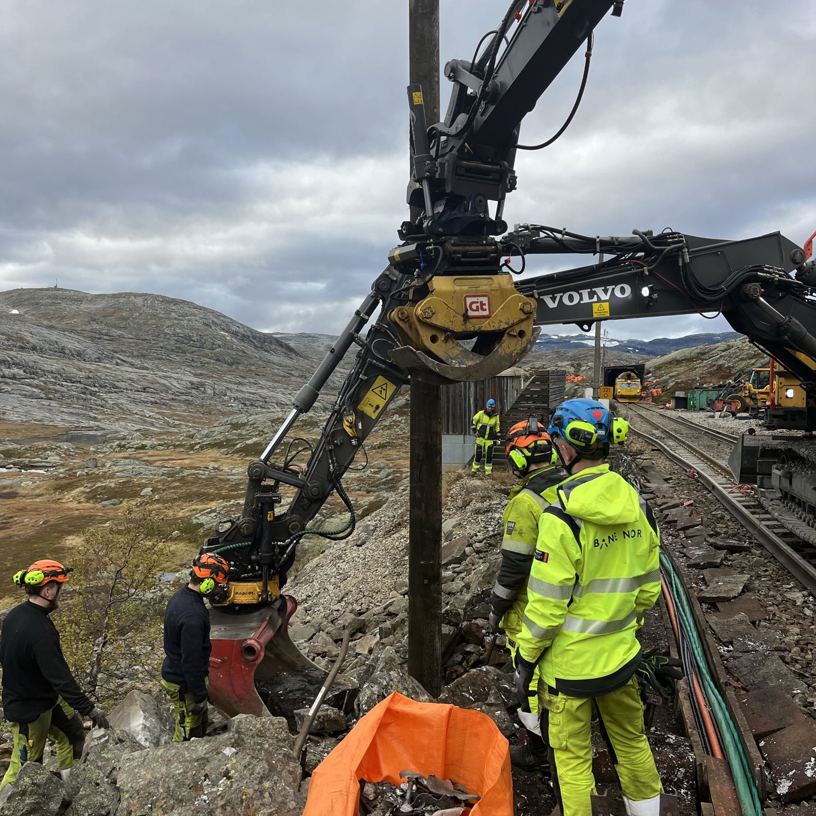 Menn i gult og oransje arbeidstøy jobber ved jernbanesporet