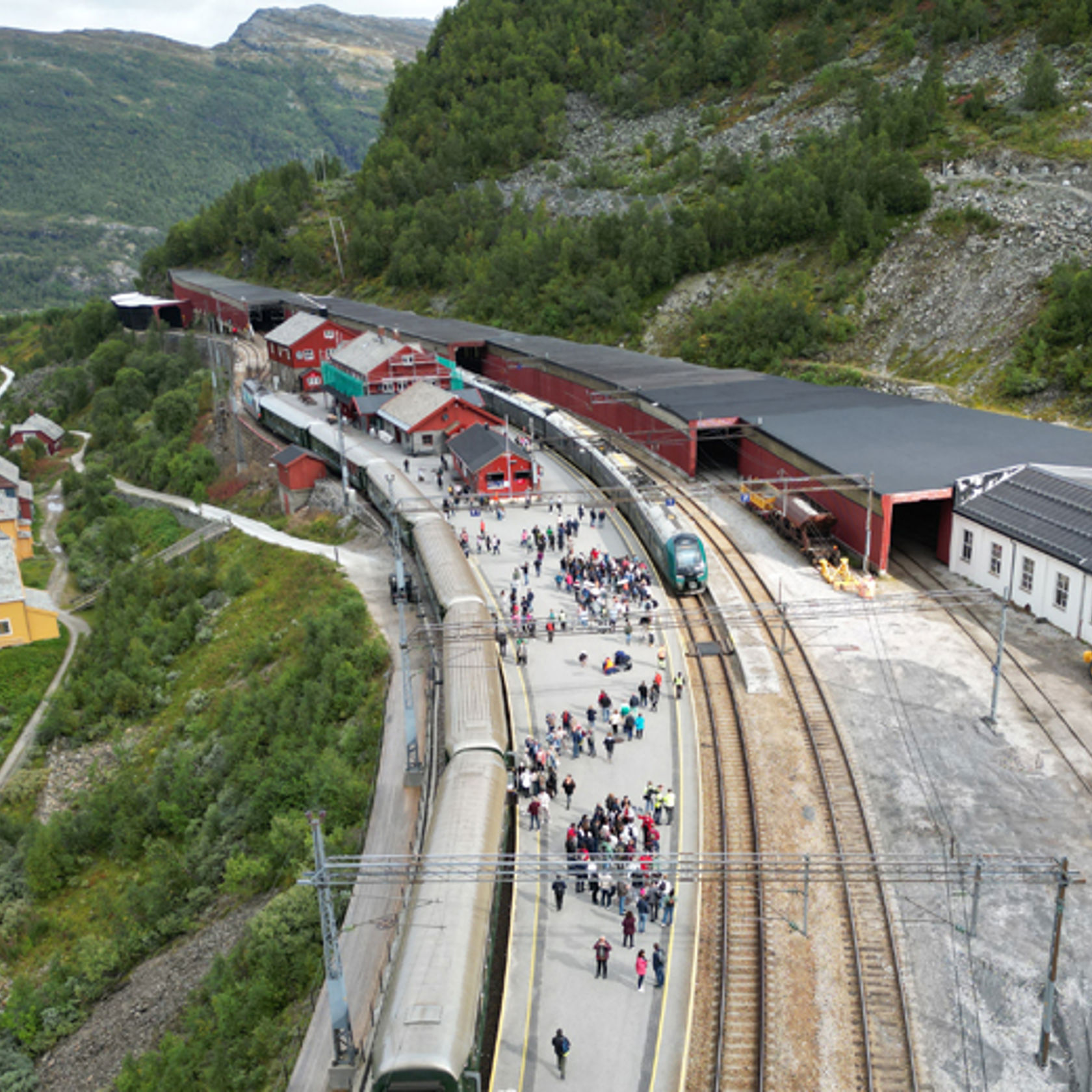 Bildet viser tog, spor, plattform og stasjonsbygninger