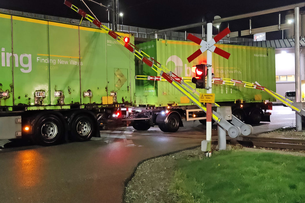 Et vogntog står midt i planovergangen. Bommene ligger oppe på taket av lastebilen.