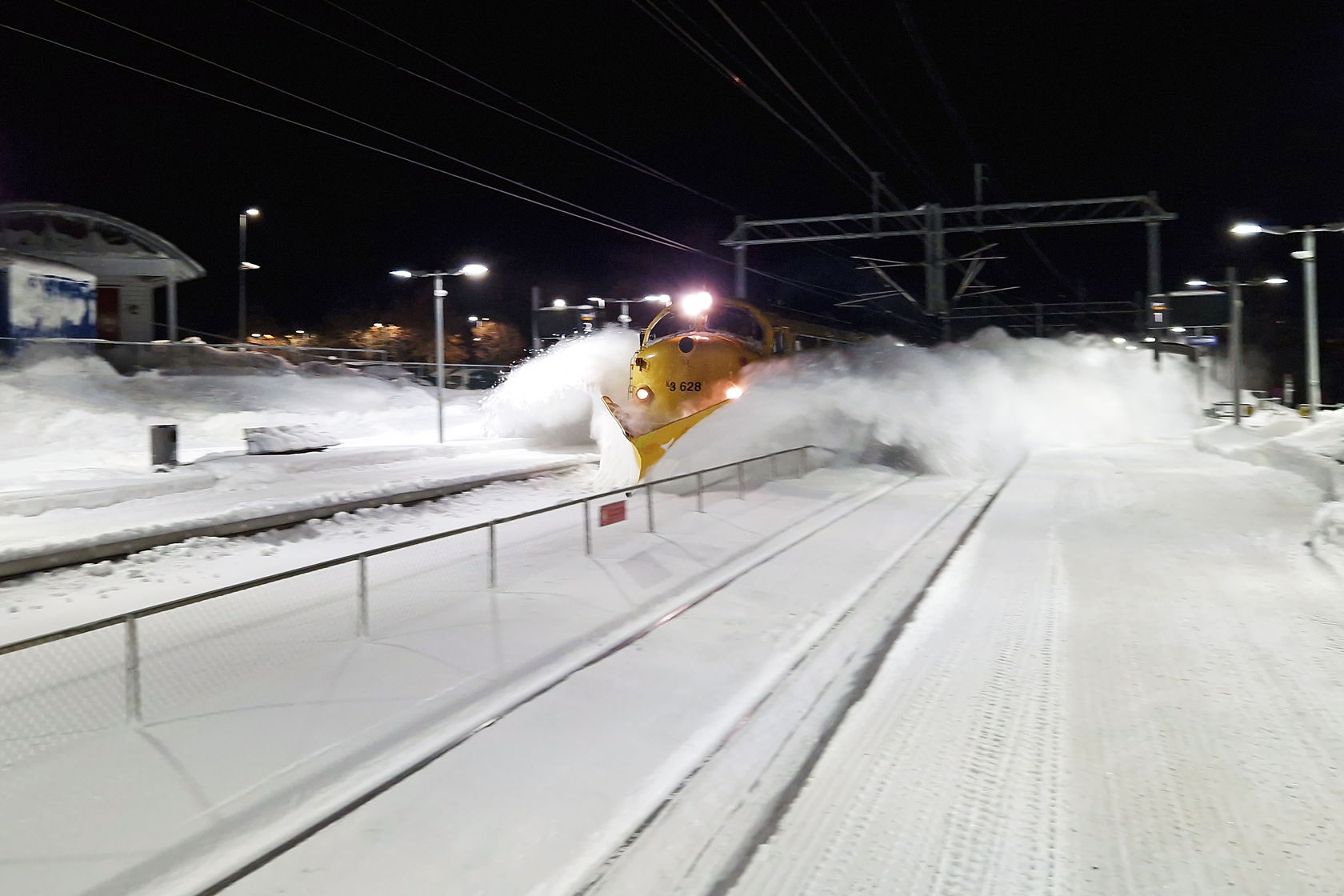 Et tog med plog brøyter seg gjennom snøen.