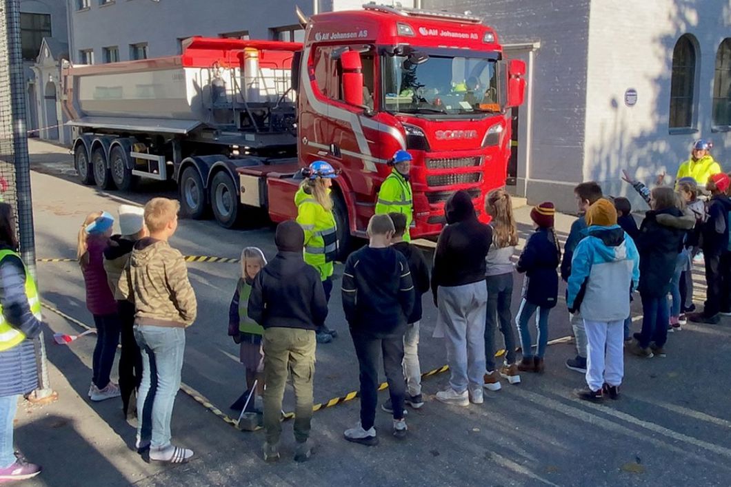 Bilde av lastebil, mennesker i vernetøy og barn.